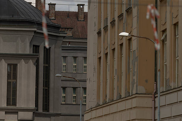 moody narrow european street between facades, lamp and red striped tape signal maintenance, muted ochre