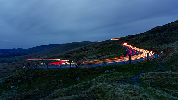 istock Winding mountain pass with car light trails at dusk 2246873293