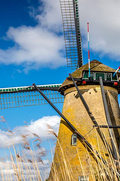 In Zaanse Schans, Netherlands a historic wooden windmill stands out against a clear blue sky on a sunny winter day.