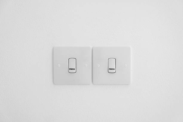 Two modern white light switches mounted on a clean textured wall in a minimal interior setting