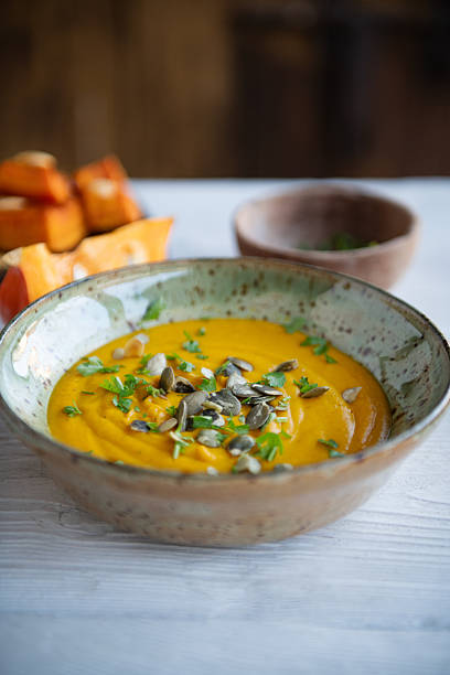 istock Pumpkin Soup in Rustic Green Bowl on Light Blue Wooden Surface Top View 2246877789