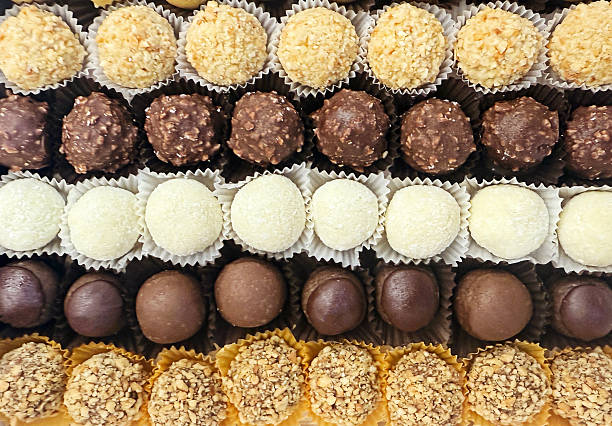 A vibrant array of bite-sized chocolates and truffles in different coatings and textures lined in neat rows, perfect for gifting, parties, and dessert tables.