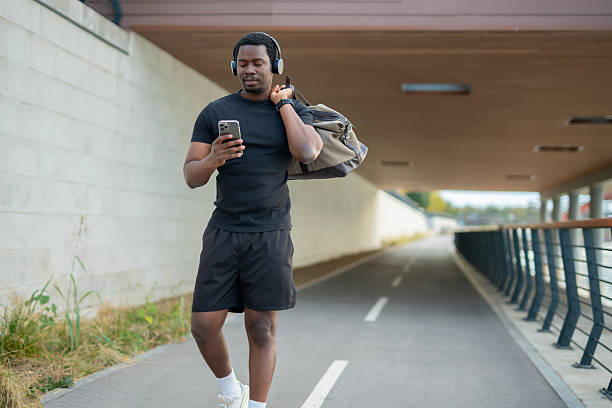 istock Man walking, checking phone, carrying gym bag 2246884333
