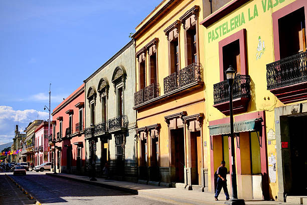 Oaxaca de Juarez, Oaxaca, Mexico – November 6, 2025: A row of colorful historic facades lines a sunlit street in central Oaxaca.