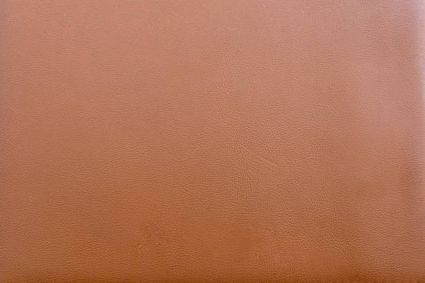Full frame close up of a smooth richly colored brown tanned leather texture with subtle grain detail presenting an even surface