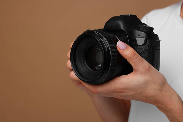 istock Photographer with camera on brown background, closeup. Space for text 2246893212