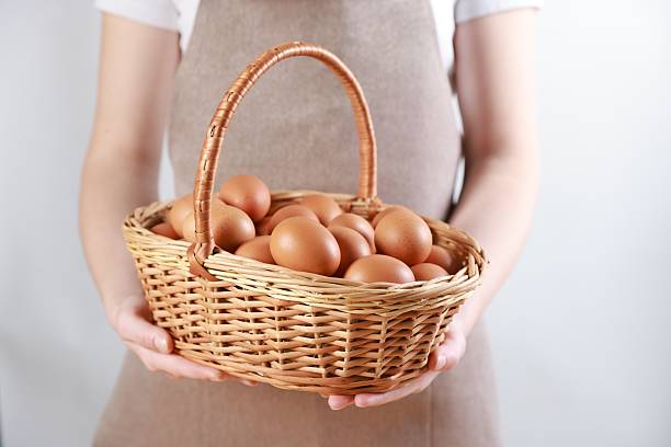 istock Woman with basket of eggs on light background, closeup 2246897196
