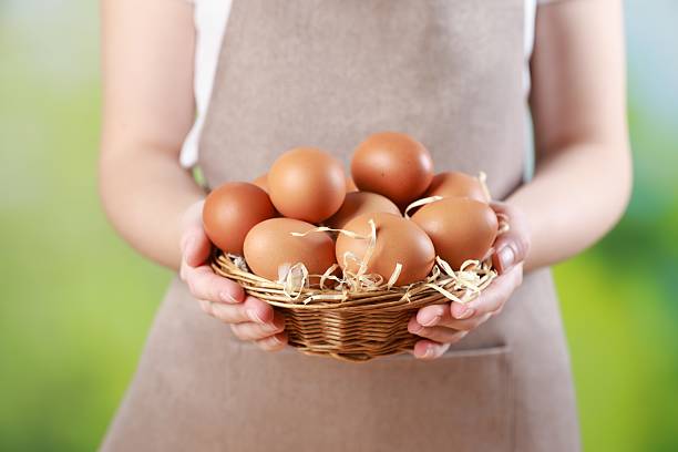 istock Woman with basket of eggs on blurred background, closeup 2246897213