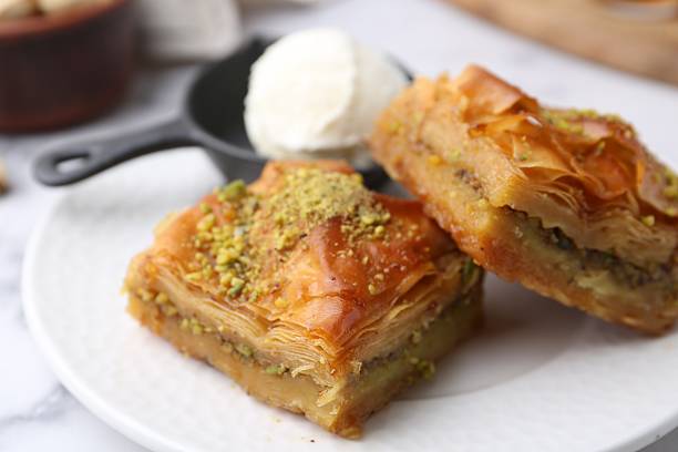 istock Delicious baklava with crushed nuts and ice cream on white table, closeup 2246897784