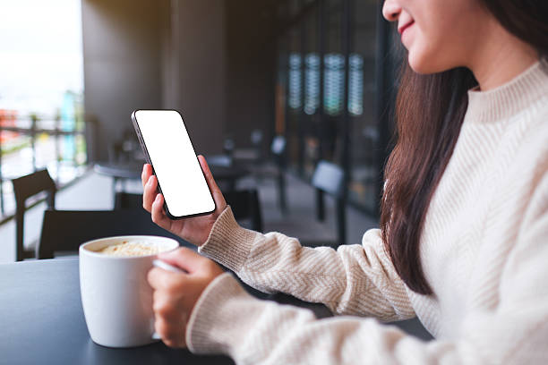 istock Closeup image of a woman holding and using mobile phone while drinking coffee in cafe 2246902151