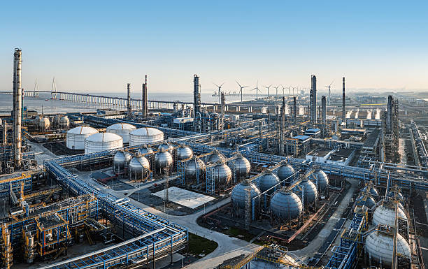 istock Coastal oil refinery with storage tanks and wind turbines. 2246916559