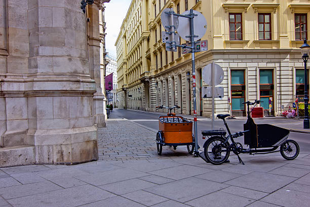 Quiet, narrow street in Vienna, lined with historic yellow buildings, showing two cargo bikes