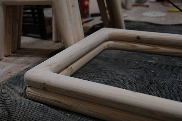 Close-up of smooth, sanded wooden chair frame components resting on a textured workshop mat. The image highlights craftsmanship, woodworking details, and the furniture-making process inside a carpentry shop. Ideal for themes related to woodworking, furniture production, DIY projects, tools, and artisan craftsmanship.