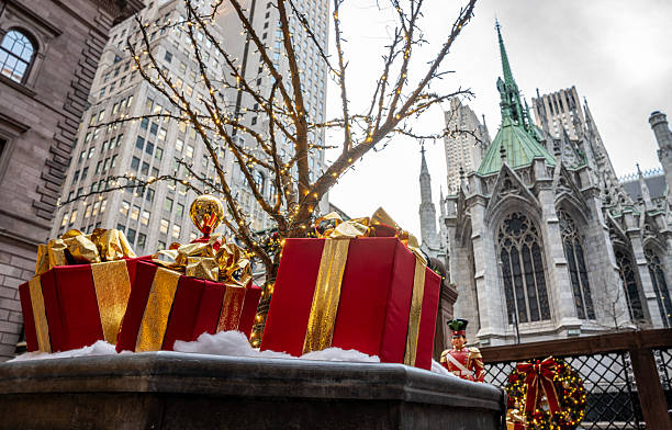 Festive Christmas gift boxes decorated with golden ribbons stand in front of the iconic St. Patrick’s Cathedral in New York City