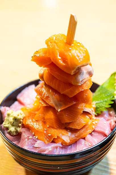 An amazing tall stack of salmon sashimi on fatty tuna bowl