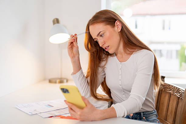 istock Woman focused on smartphone while managing paperwork at home desk 2246926645
