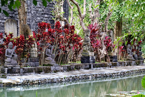 istock Stone statues sit peacefully along a pond surrounded by lush tropical plants 2246926651