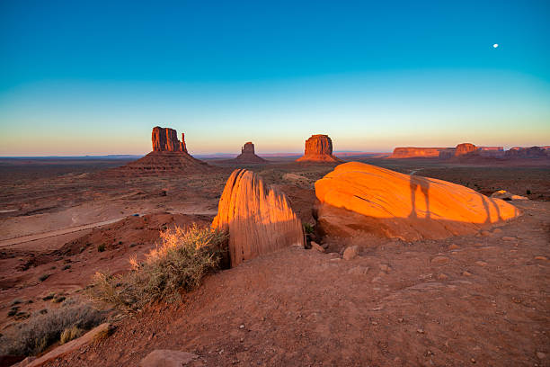 Vast Monument Valley desert landscape in summer under bright clear blue sky with red rocks.
