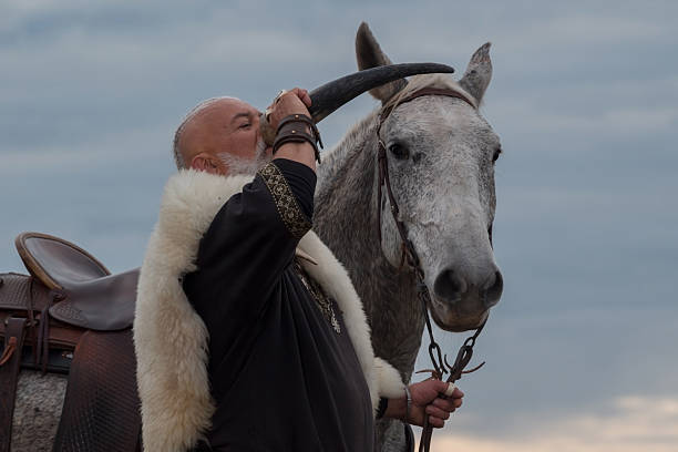 istock A rugged Viking man with a white beard, dressed in traditional attire, drinking from a horn against a stunning sunset background, showcasing strength, heritage, and heroic spirit 2246928364
