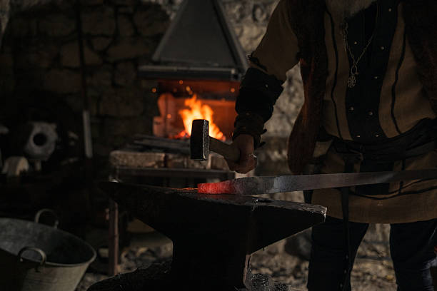 Asian manual worker heating a metal workpiece. Blacksmith's workshop in Malaysia.