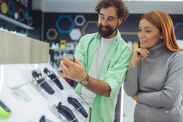 istock Loving couple examining electric shavers or beard trimmers on a display shelf in a electronics store 2246929144