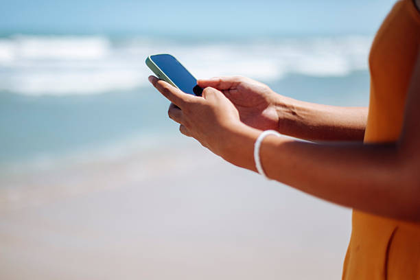 istock Mobile Close-up of Hand Holding Smartphone Outdoors on the Beach 2246929865