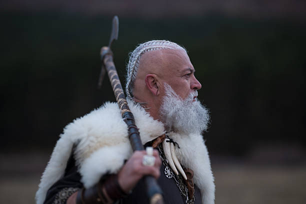 Viking warrior with axe standing on mountain cliff, wearing fur cloak and leather armor, overlooking dramatic landscape. Historical Nordic fighter, strength and adventure concept.