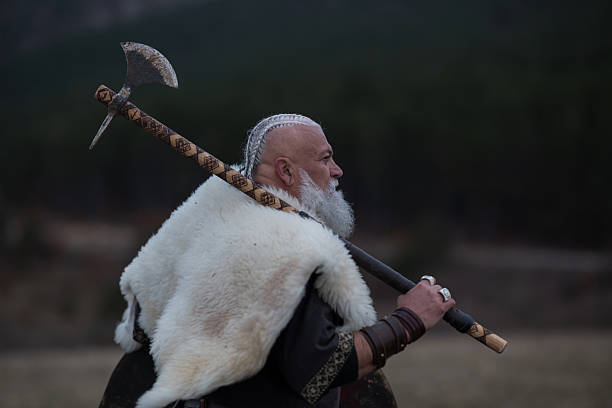 istock Viking warrior with axe standing on mountain cliff, wearing fur cloak and leather armor, overlooking dramatic landscape. Historical Nordic fighter 2246930745