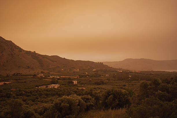 The photograph captures the eerie and surreal atmosphere of the island during a major dust event from africa, highlighting the low visibility and the striking discoloration of the air