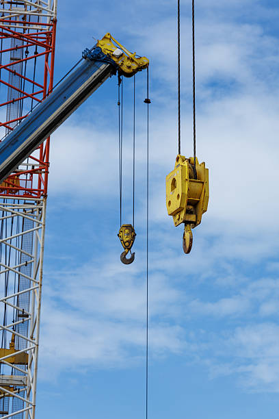 istock Portrait View of Construction Site Cranes Lifting Yellow Hoist Hooks Under Blue Sky 2246931492