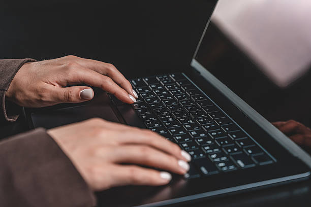 istock Close-up of hands typing on laptop keyboard in low light setting on black background. 2246932741