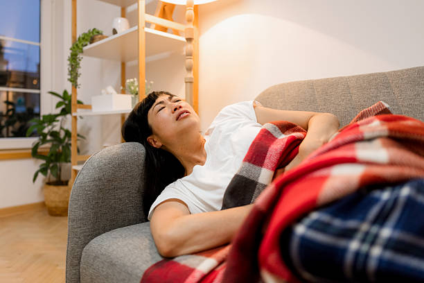 istock Woman curled slightly on sofa due to stomach discomfort 2246933427