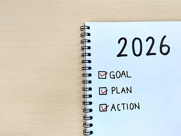 istock New year 2026 resolution concept. Goal, plan and action written on a notebook with wooden table background 2246936283
