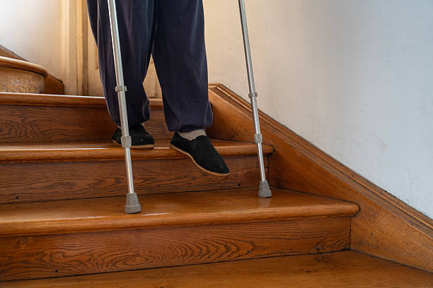 istock Senior man moving down the indoors stairs using crutches 2246941636