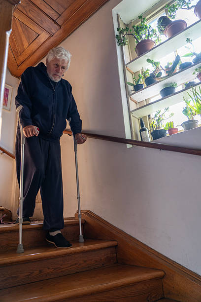 istock Senior man moving down the indoors stairs using crutches 2246941649