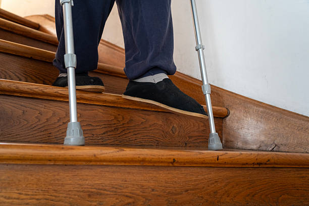 istock Senior man moving down the indoors stairs using crutches 2246941657