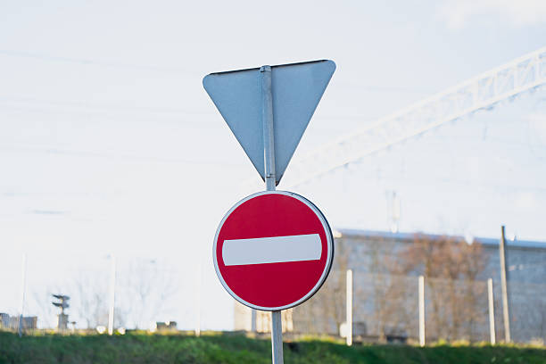 istock Red circular no entry symbol mounted on post with unused triangular frame overhead in outdoor transit zone illustrating regulated direction control and roadway prohibition marker placement 2246941681
