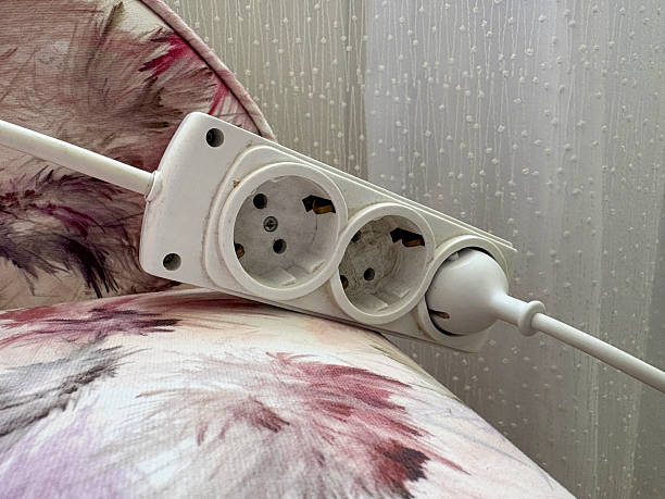 istock Electrical outlet and electric plug connection. Extension cordon the sofa 2246945918