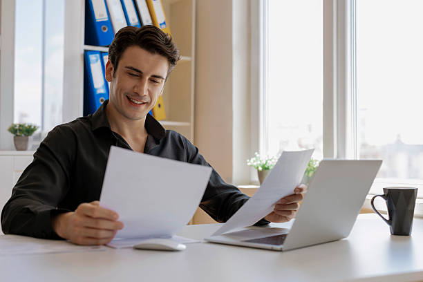 istock Businessman smiling and looking at papers 2246950415