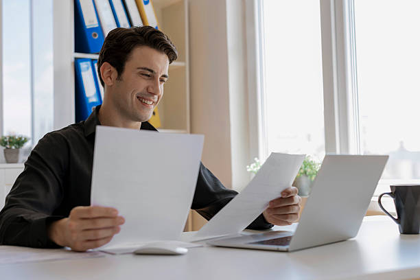 istock Businessman smiling and looking at papers 2246950492