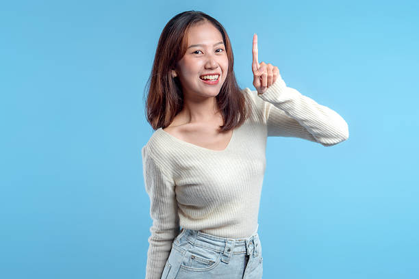 istock Smiling Indonesian Woman Pointing Up Confidently 2246959780