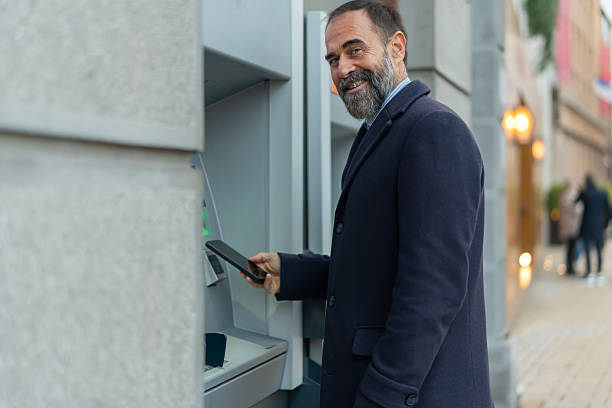 istock Mature man using phone for contactless atm transaction 2246960014
