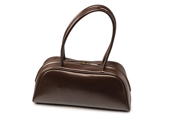 Woman leather handbag with phone and lipstick. On white background, copy space.