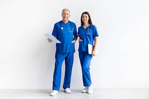 istock Two doctors wearing blue medical uniform standing together on white studio background 2246965762