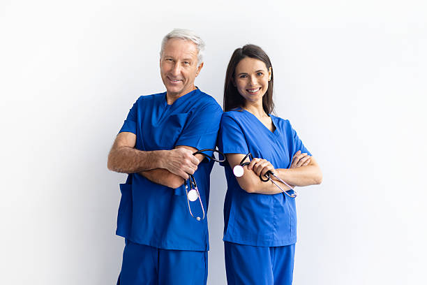 istock Two doctors in blue scrubs standing with arms crossed on white background 2246967053