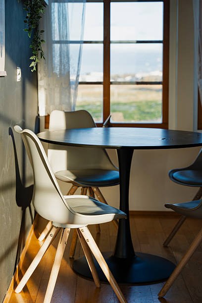istock Sunlit dining area with a round table and chairs, view to the outside world. 2246974705