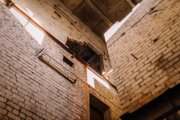 Abandoned industrial building with exposed brick walls and natural light streaming through broken windows, creating a dramatic atmosphere of decay and history