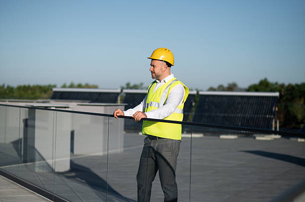 istock Technician in safety vest standing near solar panel field 2246990219