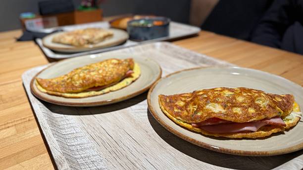 Omelette with ham on a wooden table in a cozy dining setting with soft lighting
