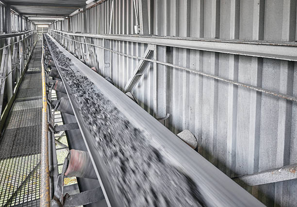 Belt conveyor transporting coal in a heating plant, selective focus.